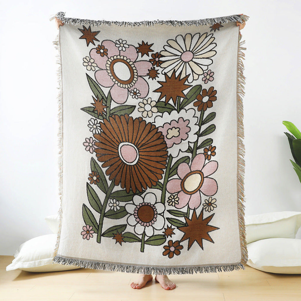 Floral patterned throw blanket with tassels on a white background