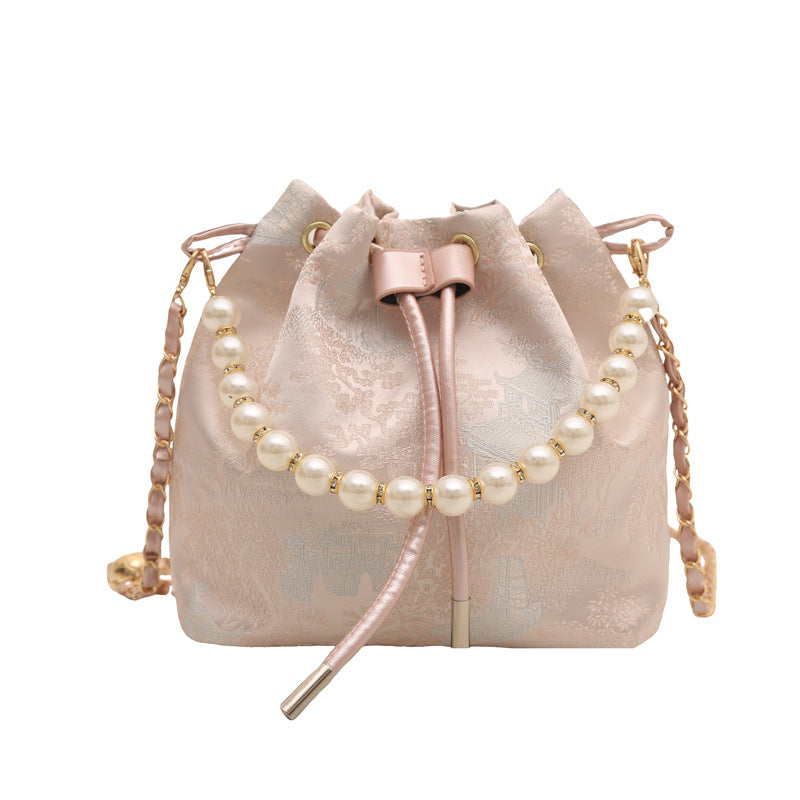 Pink drawstring bag with pearl details on a white background