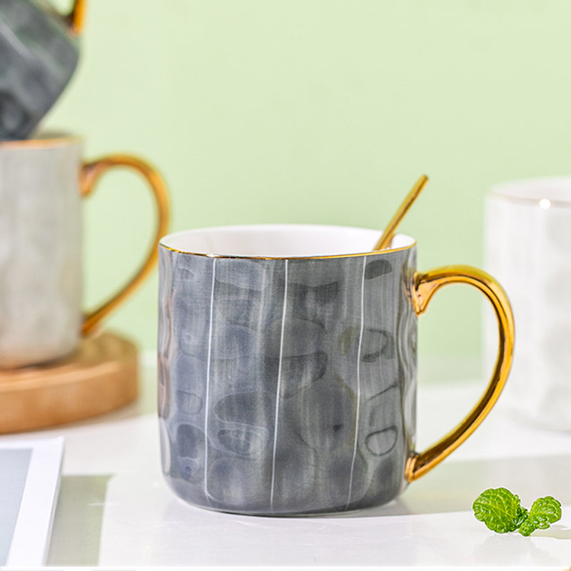 Gray marble-patterned mug with gold handle on a light green background