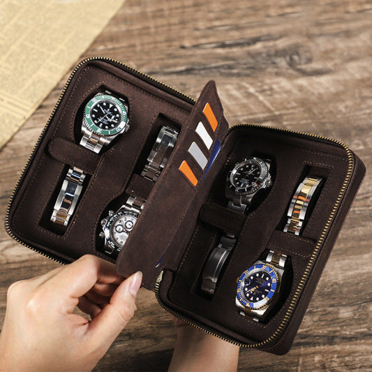 Brown watch case with four watches on a wooden surface