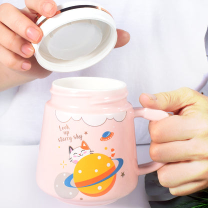 Pink mug with cartoon design held by a person against a white background