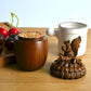 Wooden container with a lid featuring a squirrel design on a wooden surface.