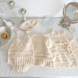 Set of baby crocheted outfit with overalls, dress, and hat on a white surface.