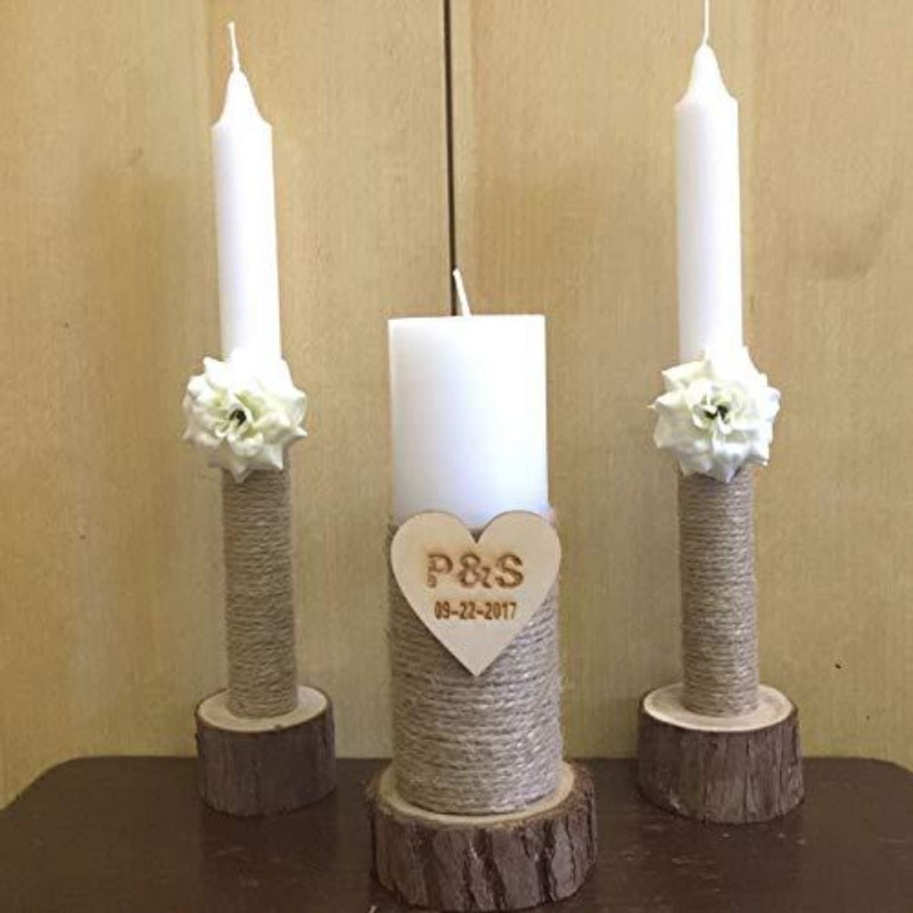 Three candles on wooden stands with floral decorations and a heart-shaped plaque on a beige background