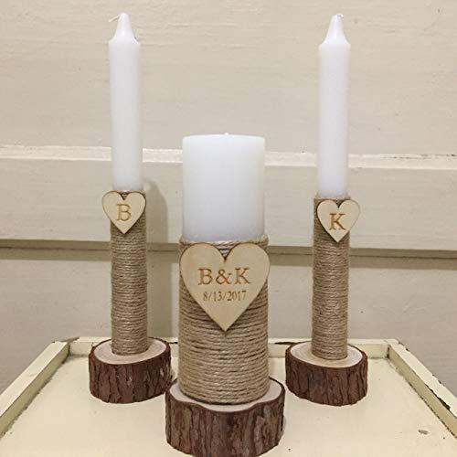 Three candles in rustic holders with wooden hearts and initials on a white surface.