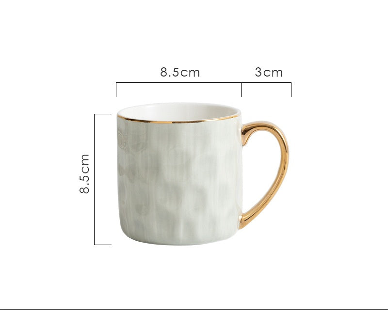White ceramic mug with gold handle and measurements on a white background