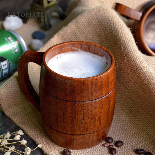 Wooden mug filled with a frothy beverage on a textured surface with coffee beans.